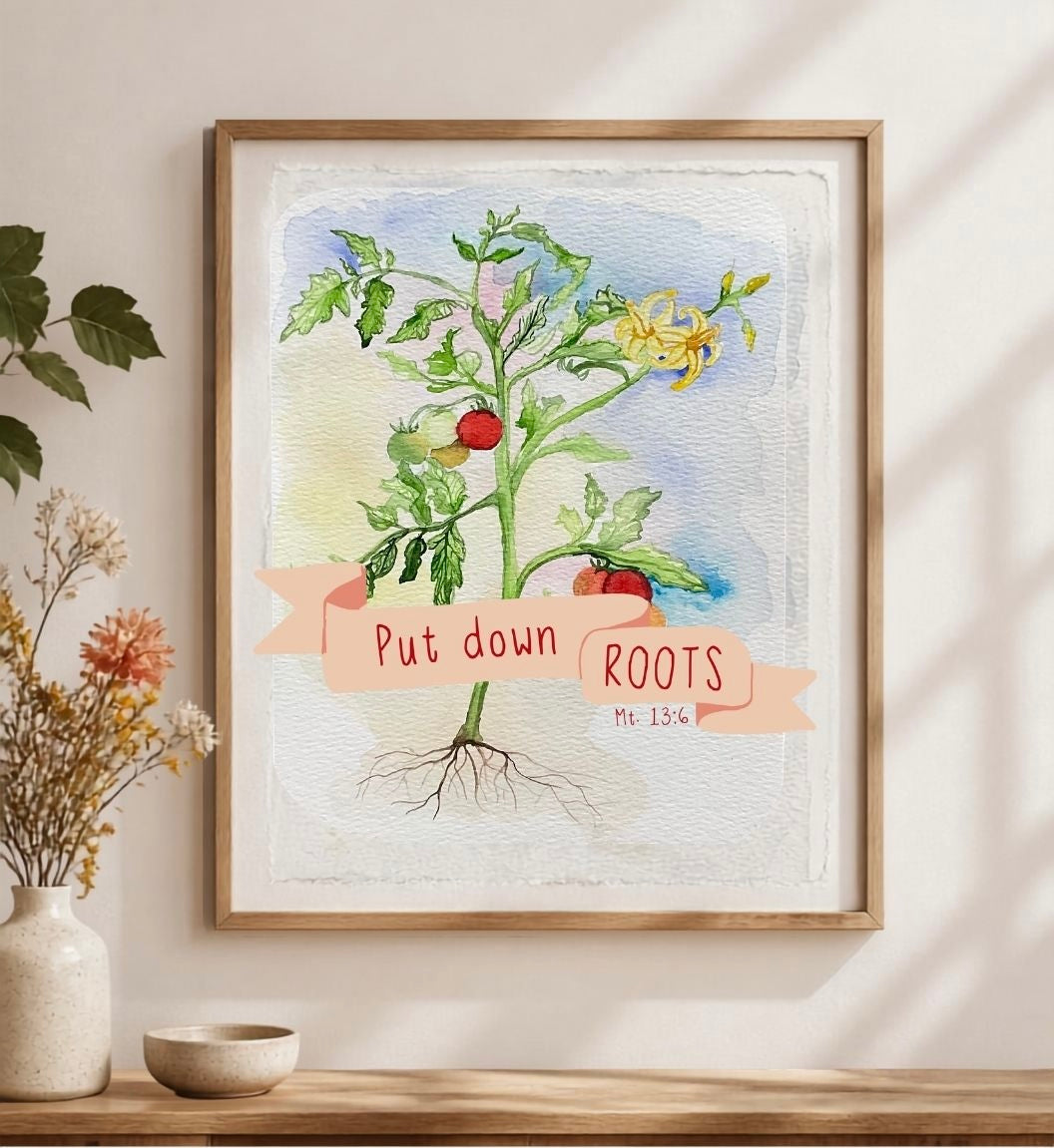 A framed botanical art print featuring a watercolor tomato plant with the text 'Put down ROOTS Mt. 12:36' on a banner, displayed on a shelf in a styled interior setting.